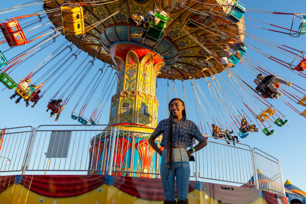 Woman smiling in front of swing ride at the Fair