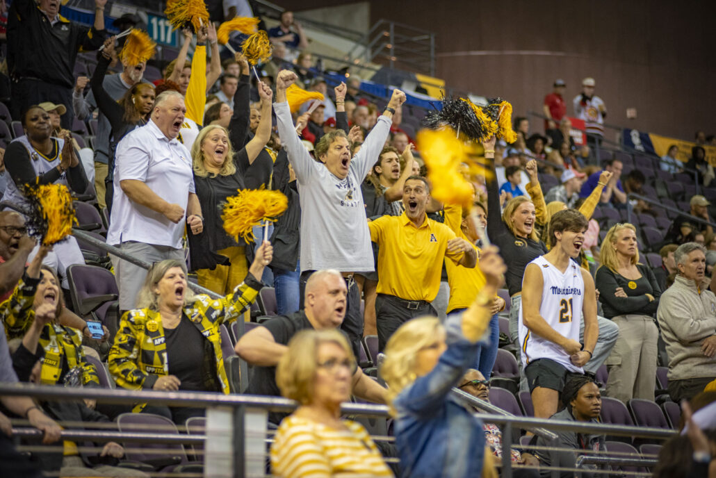 Fans in the stands cheering and celebrating at the Sun Belt Basketball Championship.