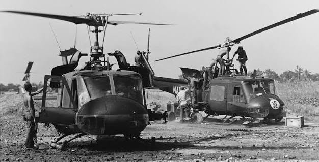 Black and white photograph of the “Seawolves,” Helicopter Attack Squadron (Light) 3. Two helicoptors and men working on them.