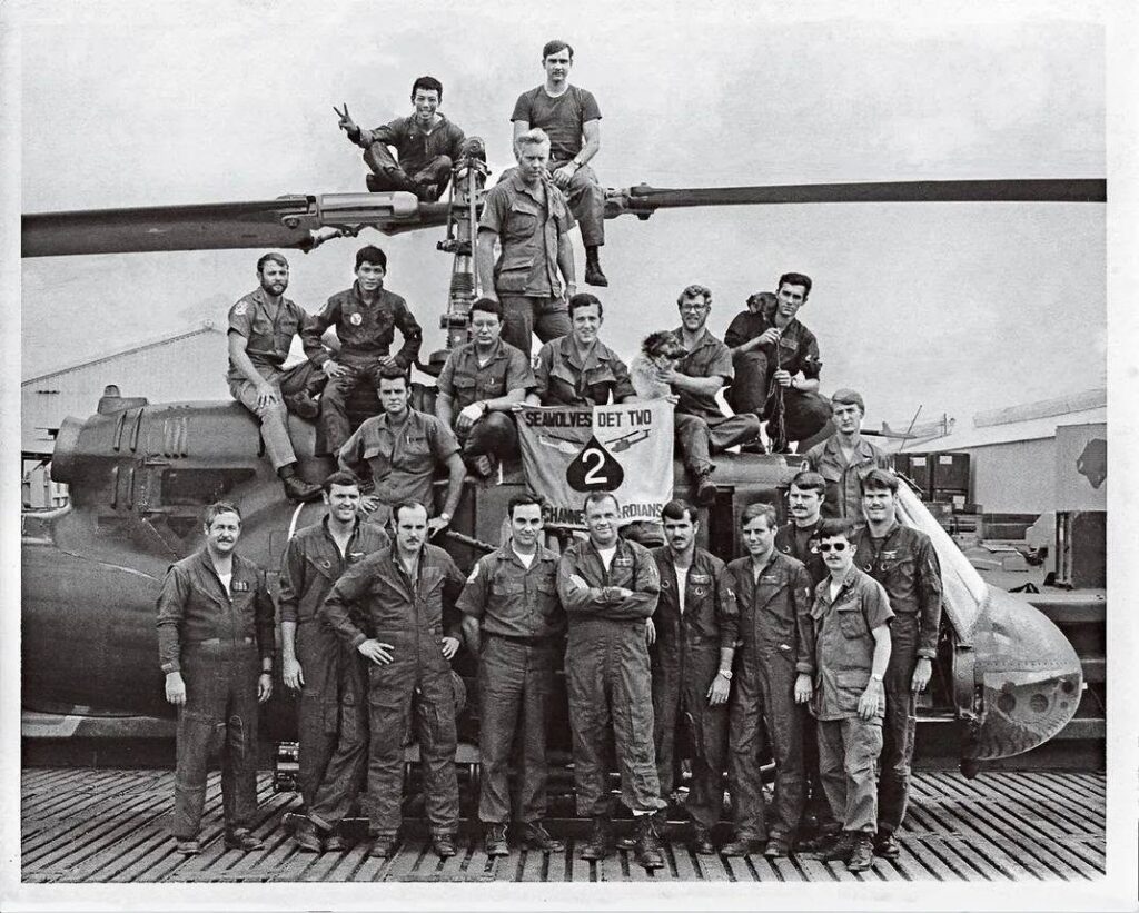 Black and white photo of men in front of a helicopter. Known as the “Seawolves,” Helicopter Attack Squadron (Light) 3.